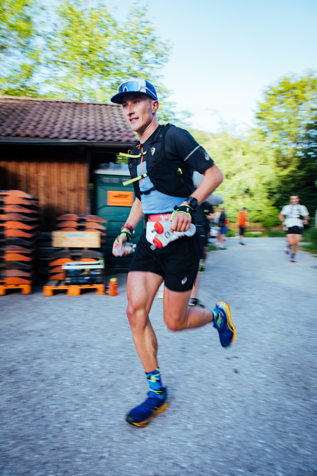ASICS athlete in motion blur passing an aid station on course