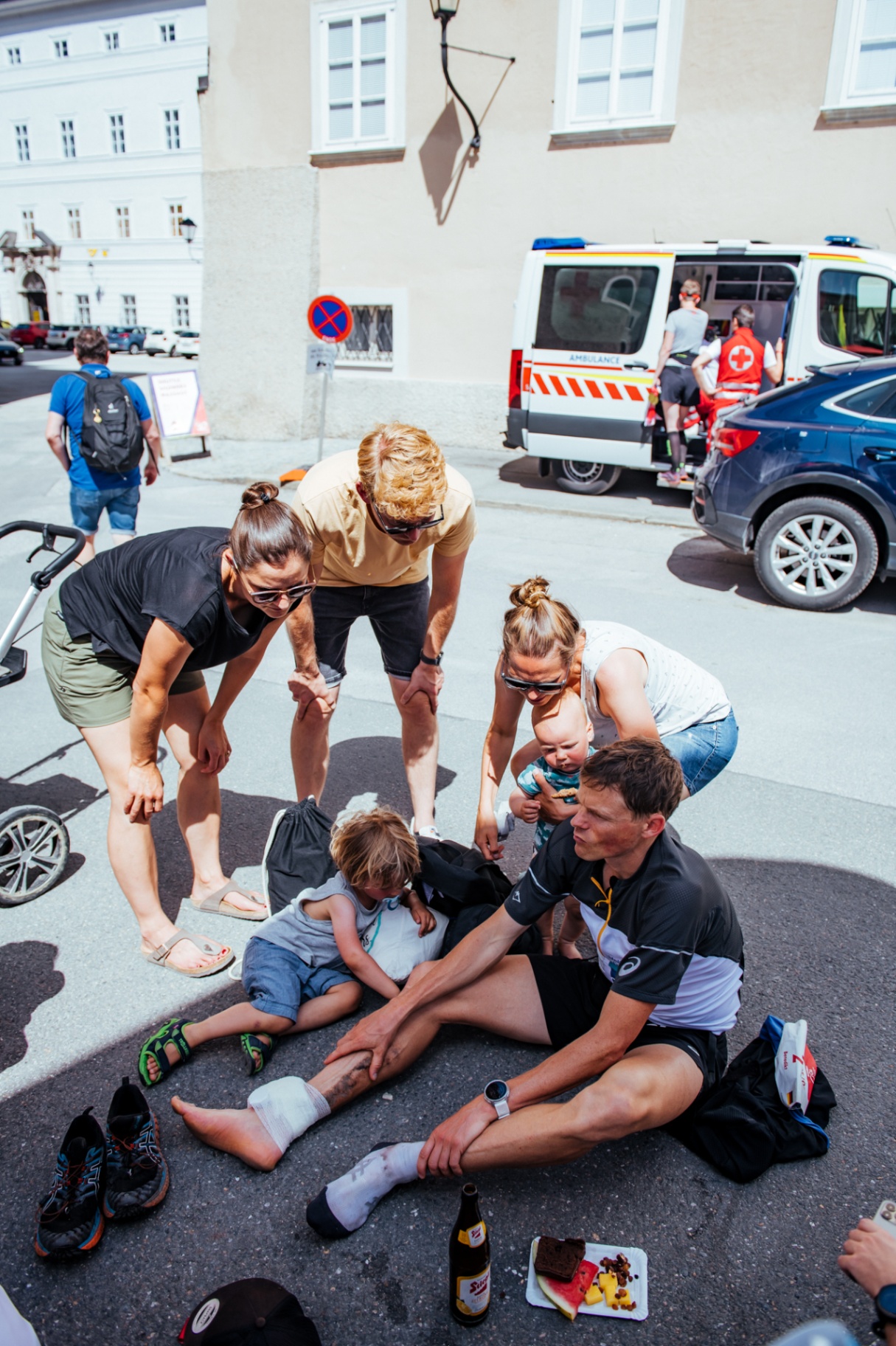 Athlete on the cobbles post-race with family and medics in Salzburg