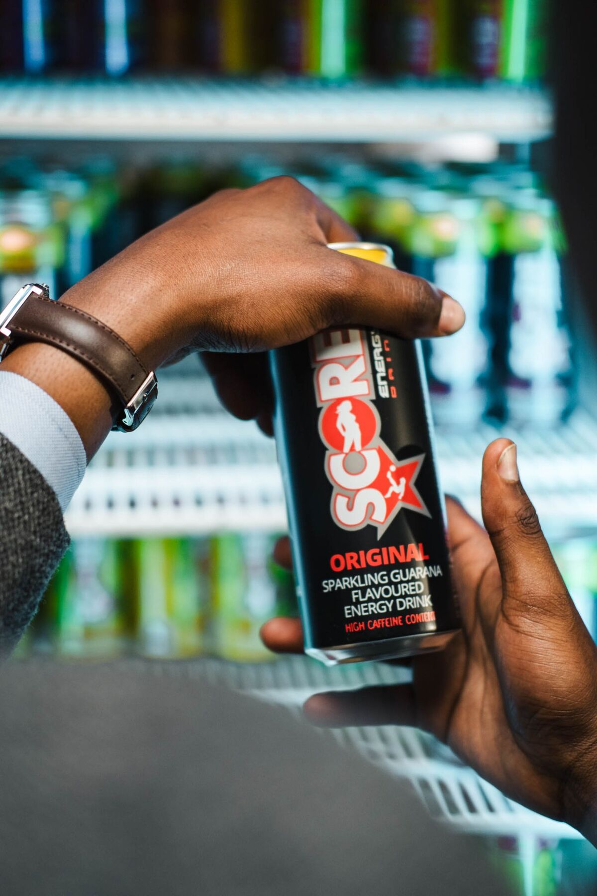 Hands holding a can of Score Energy Original in front of a fridge