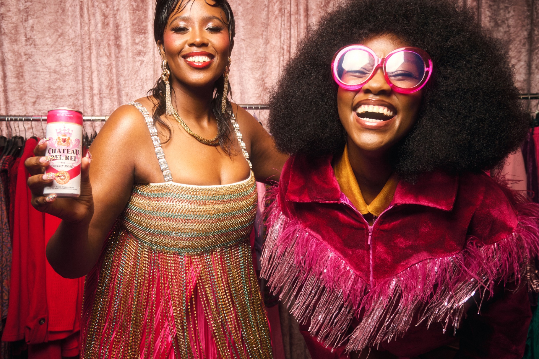 Two cast members backstage with a Château Del Rei Sweet Rosé can, era-inspired styling